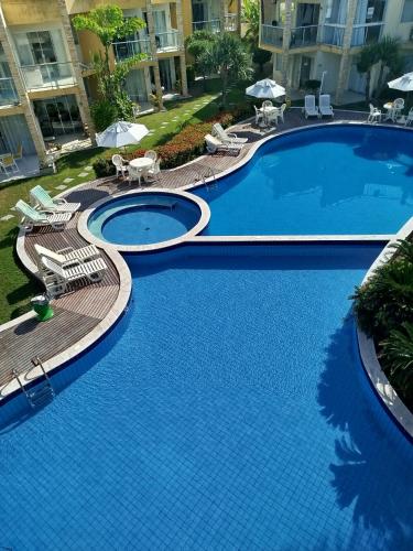 a large blue swimming pool with chairs and umbrellas at Chalé na praia in Nísia Floresta