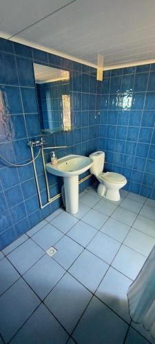 a blue tiled bathroom with a toilet and a sink at ДАЧА на Студенческой in Karolino-Buhaz