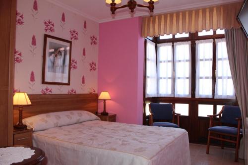 a bedroom with pink walls and a bed and a window at Casa Rural Maribel II in Cue