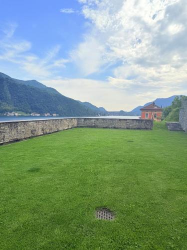 a large green field with a stone wall and a house at Gritti Palace Morcote - Lavanda in Morcote