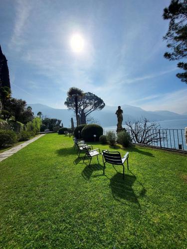 a row of benches sitting in the grass with a statue at Gritti Palace Morcote - Lavanda in Morcote