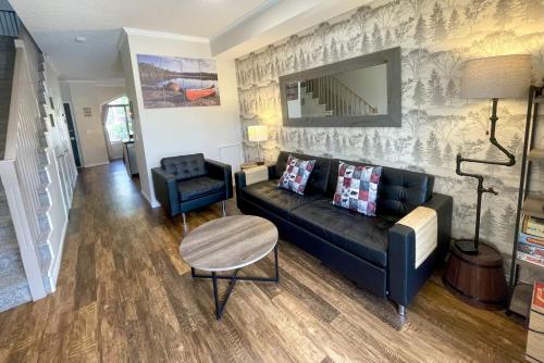 a living room with a black couch and a chair at Renovated Chalet at Mystic Springs, Mountain Views, Pets Welcome! in Canmore