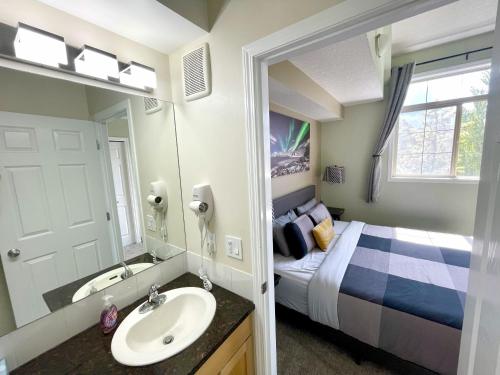 a bathroom with a bed and a sink and a mirror at Renovated Chalet at Mystic Springs, Mountain Views, Pets Welcome! in Canmore