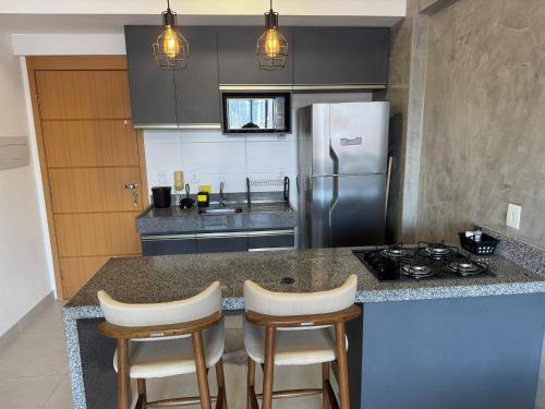 a kitchen with a counter with a stove and a refrigerator at Unique studio - loft aconchegante e bem localizado in Belém