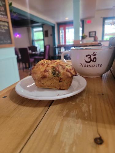a muffin on a plate next to a cup of coffee at Auberge d'Anjou-Sūrya Café in Petit Rocher