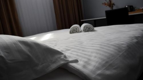 a white bed with two towels on top of it at Harmony B&B in Fălticeni
