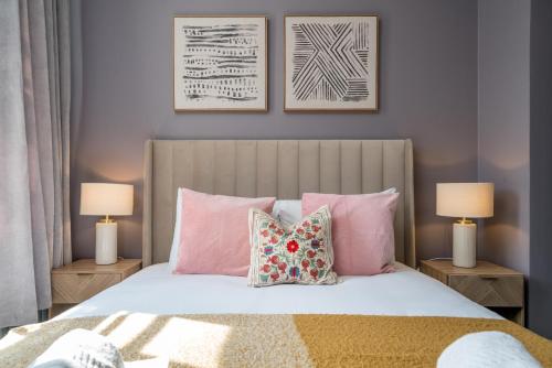 a bedroom with a bed with pink pillows and two lamps at Victoria 2 bedroom flat - Buckingham palace in London