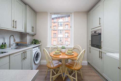 a kitchen with a table with chairs and a sink at Victoria 2 bedroom flat - Buckingham palace in London