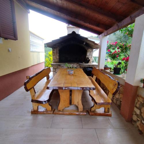 a wooden table and chairs with a fireplace on a patio at Apartments Grbac Veli Rat-Seaside in Veli Rat