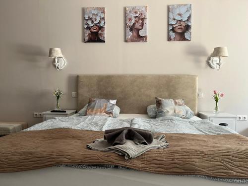a bed in a bedroom with four pictures on the wall at Guest House Romantika Panzio in Gyula
