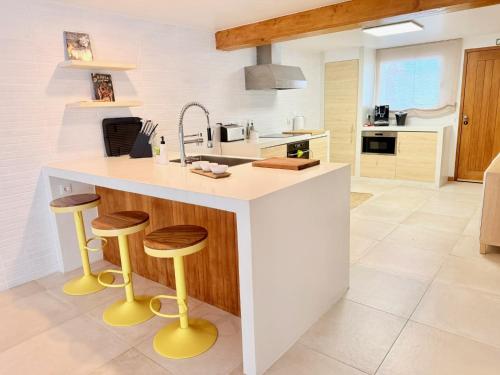 a kitchen with a white counter and wooden stools at Casa da Pedreira in Porto Santo