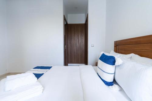 a bedroom with a white bed with blue and white pillows at Détente en Famille, Piscine, Plage à Proximité in Bouznika