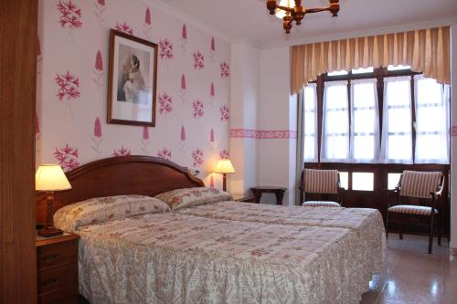 1 dormitorio con 1 cama con papel pintado de flores rosas en Casa Rural Maribel II, en Cue