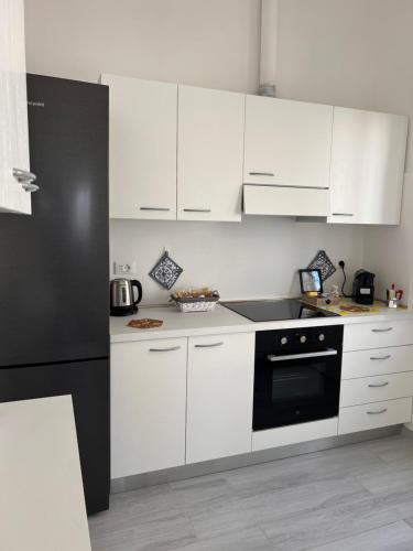 Una cocina con gabinetes blancos y un refrigerador negro. en Villa PO, en Torre Santa Sabina