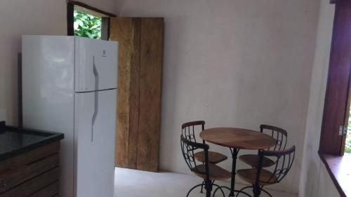 una cucina con frigorifero bianco, tavolo e sedie di Chalé ponta negra paraty a Parati