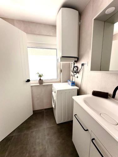 a white bathroom with a sink and a window at Villa Forever More in Kaštela