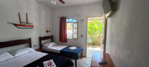 a bedroom with two beds and a window and a door at Pousada Vila das Artes in Paraty