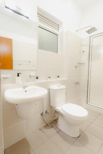 a white bathroom with a toilet and a sink at Ayrish Grand in Mount Lavinia