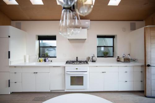 a kitchen with white cabinets and a chandelier at Private Venice Beach Luxury Bungalow, Outdoor Tub, Steps To Ocean & Abbot Kinney in Los Angeles