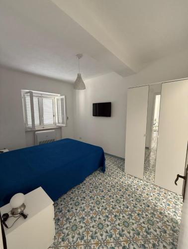 a bedroom with a blue bed and a tv at Perla Bianca Holiday Home, Forio in Forio d'Ischia