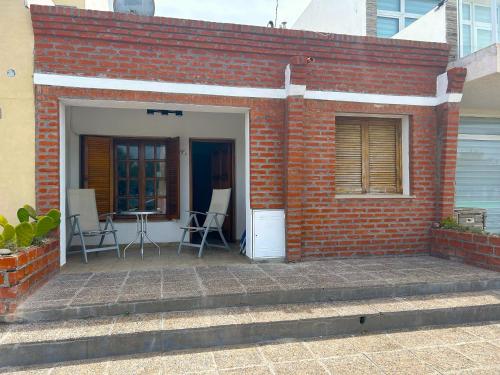 a brick building with a patio with chairs and a table at Lōla Beach House - Playa Unión in Playa Unión
