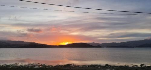 a sunset over a large body of water with mountains at Kakianau Retreat, Luxury Waterfront Apartments in Portobello