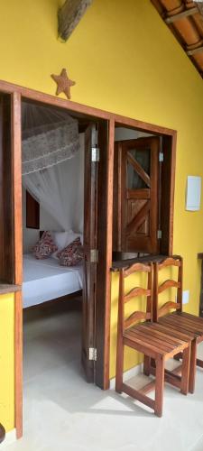 a room with a bunk bed and a wooden chair at Chalé na Praia da Tiririca in Itacaré