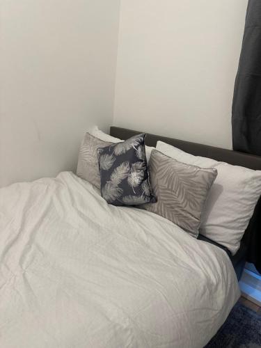 a white bed with three pillows on top of it at The Retreat On Retreat Road in Southend-on-Sea