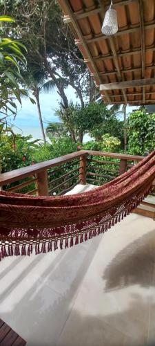 a hammock on a porch with a view of the ocean at Chalé na Praia da Tiririca in Itacaré