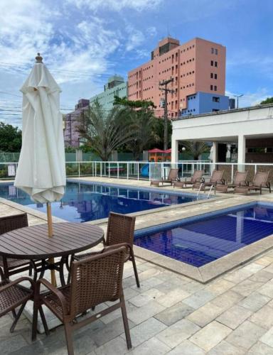 a table with an umbrella next to a swimming pool at SPAZIO GOMES E COSTA vip in Cabedelo