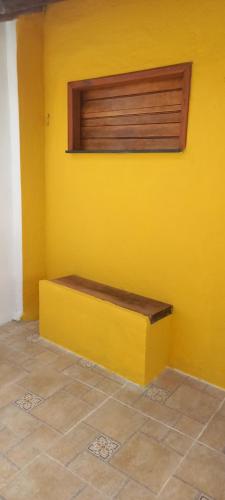 a yellow wall with a bench in a room at Chalé na Praia da Tiririca in Itacaré