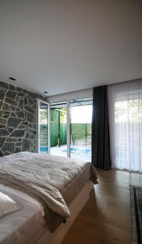 a bedroom with a large bed with a stone wall at Riverside Private Pool&Halal Suite in Shkodër