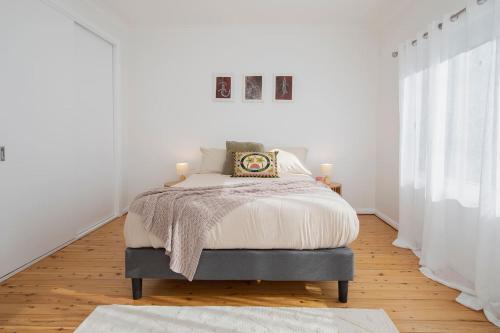 una camera bianca con un letto in una stanza di Serena Cottage - Sunlit Escape by Woy Woy Bay Wharf a Woy Woy