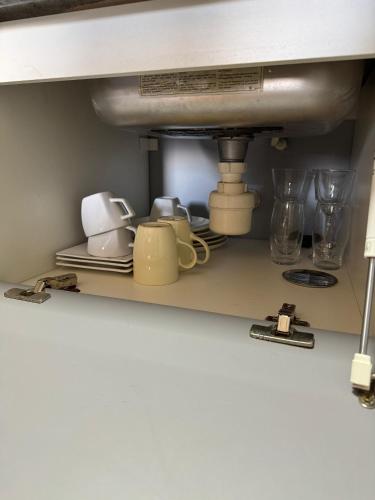 a shelf under a sink with cups and glasses at Flat 706 próximo à praia - Condomínio Biarritz in São Luís