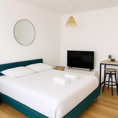 une chambre avec un lit et une télévision à écran plat dans l'établissement Le Nid Marin - studio cosy à Lorient, à Lorient