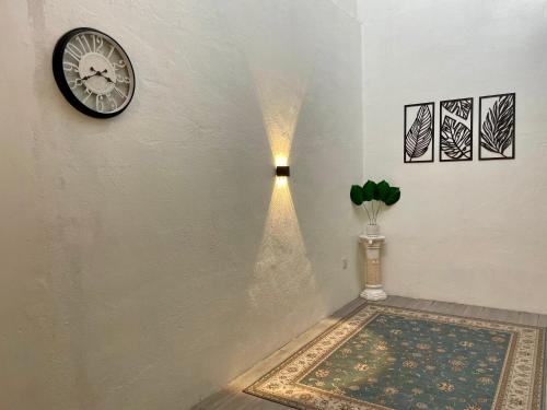 a hallway with a clock on the wall and a rug at RH Homestay Mentakab-Temerloh. in Mentekab