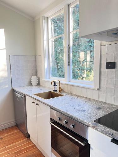 a white kitchen with a sink and a window at Charming 100 year old Villa in Te Kuiti