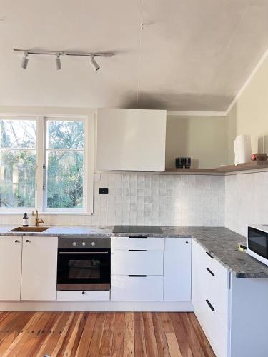 a kitchen with white cabinets and a counter top at Charming 100 year old Villa in Te Kuiti