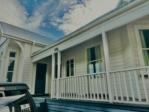 a white house with a porch with a white railing at Charming 100 year old Villa in Te Kuiti