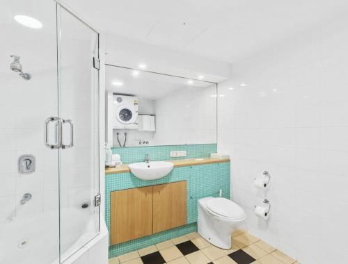 a bathroom with a toilet and a sink and a mirror at The Entrance Waterfront Apartment 505 in The Entrance