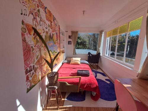 a bedroom with a red bed and a window at Sunrays Stay - Stylish Retreat in New Plymouth