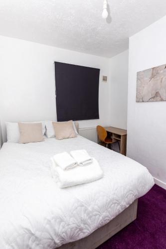 a white bed with two towels on top of it at 4 Bedroom House in Wolverhampton Sleeps 8 Ideal for Contractors in Fallings Park