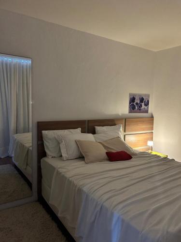 a bedroom with a large bed with white sheets at Nossa casa, nosso lar in Belo Horizonte