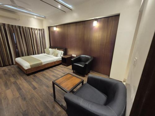 a hotel room with a bed and a couch and chairs at R D Hotels HSR in Bengaluru