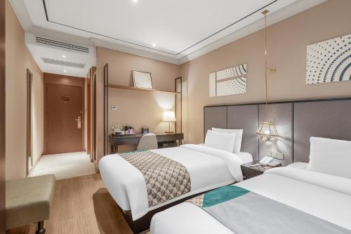 a hotel room with two beds and a desk at Yitel Premium Shanghai Jing'an Temple in Shanghai