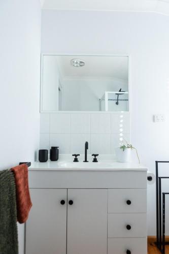 a white kitchen with a sink and a mirror at North Central Spacious Charmer in Shepparton