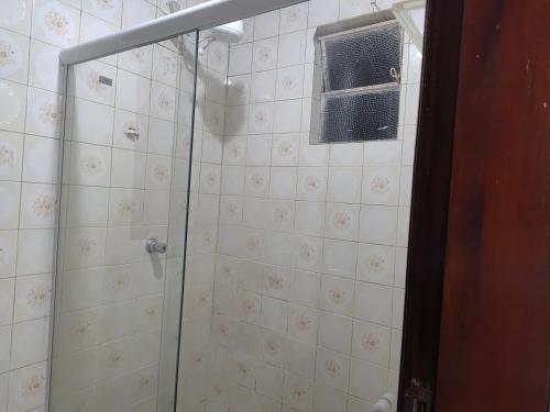 a shower with a glass door and a window at Casa Aconchegante in Vitória da Conquista