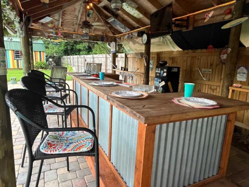 a bar in an outdoor kitchen with chairs and tables at Jan's Oasis Family Retreat Pool Bar Games & Fun in Pensacola