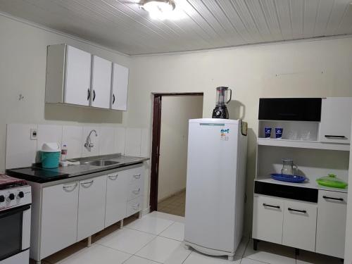 a kitchen with white cabinets and a white refrigerator at Casa Aconchegante in Vitória da Conquista
