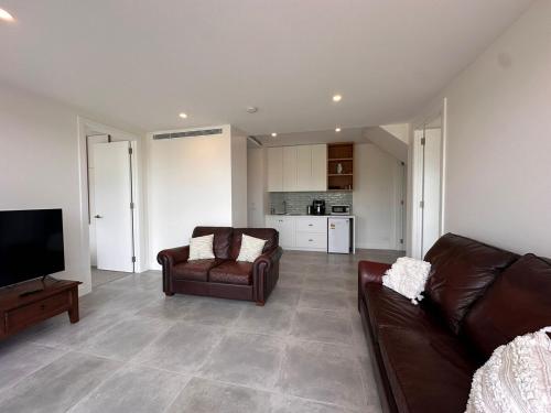a living room with two leather couches and a television at Private Getaway - Portarlington! in Portarlington